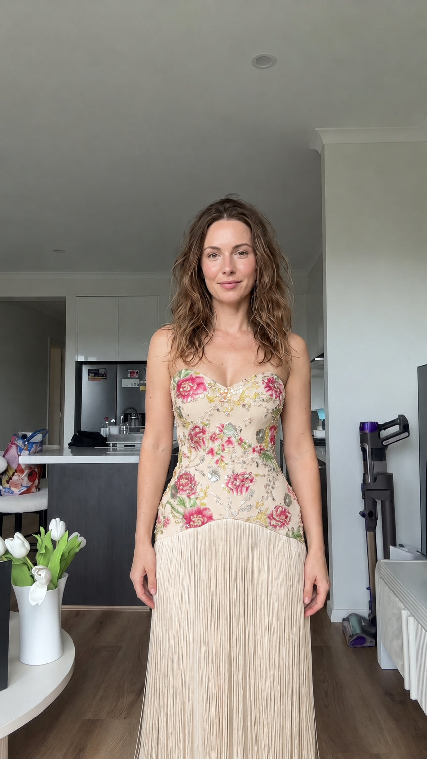 Woman wearing champagne cream floral embroidered strapless fringe maxi dress